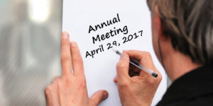Person writing Annual Meeting Information