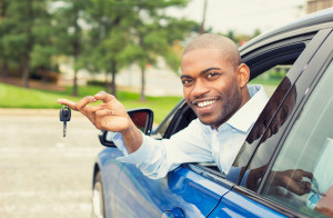 happy, smiling, young man sitting in his new car showing keys