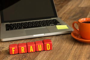 Fraud written on a wooden cube in a office desk