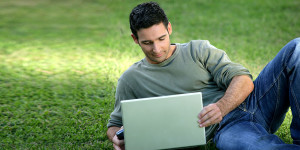 Person laying in the grass on laptop