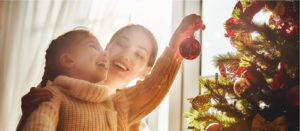 girl placing ornament on tree