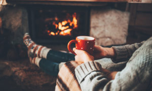 person by the fire holding a mug