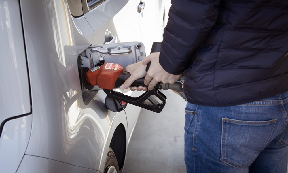 person pumping gasoline into silver vehicle