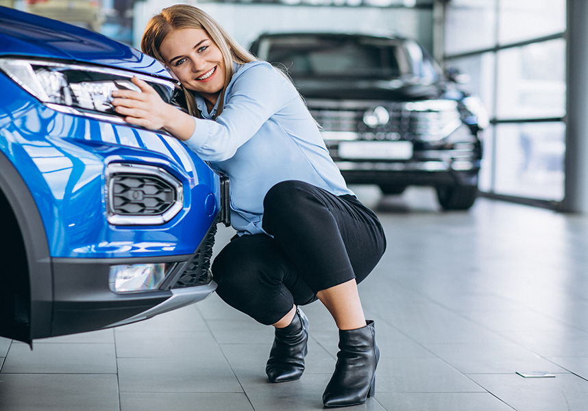 Smiling Young Woman Hugging Bumper Of Blue Vehicle Smiling Young Woman Hugging Bumper Of Blue Vehicle